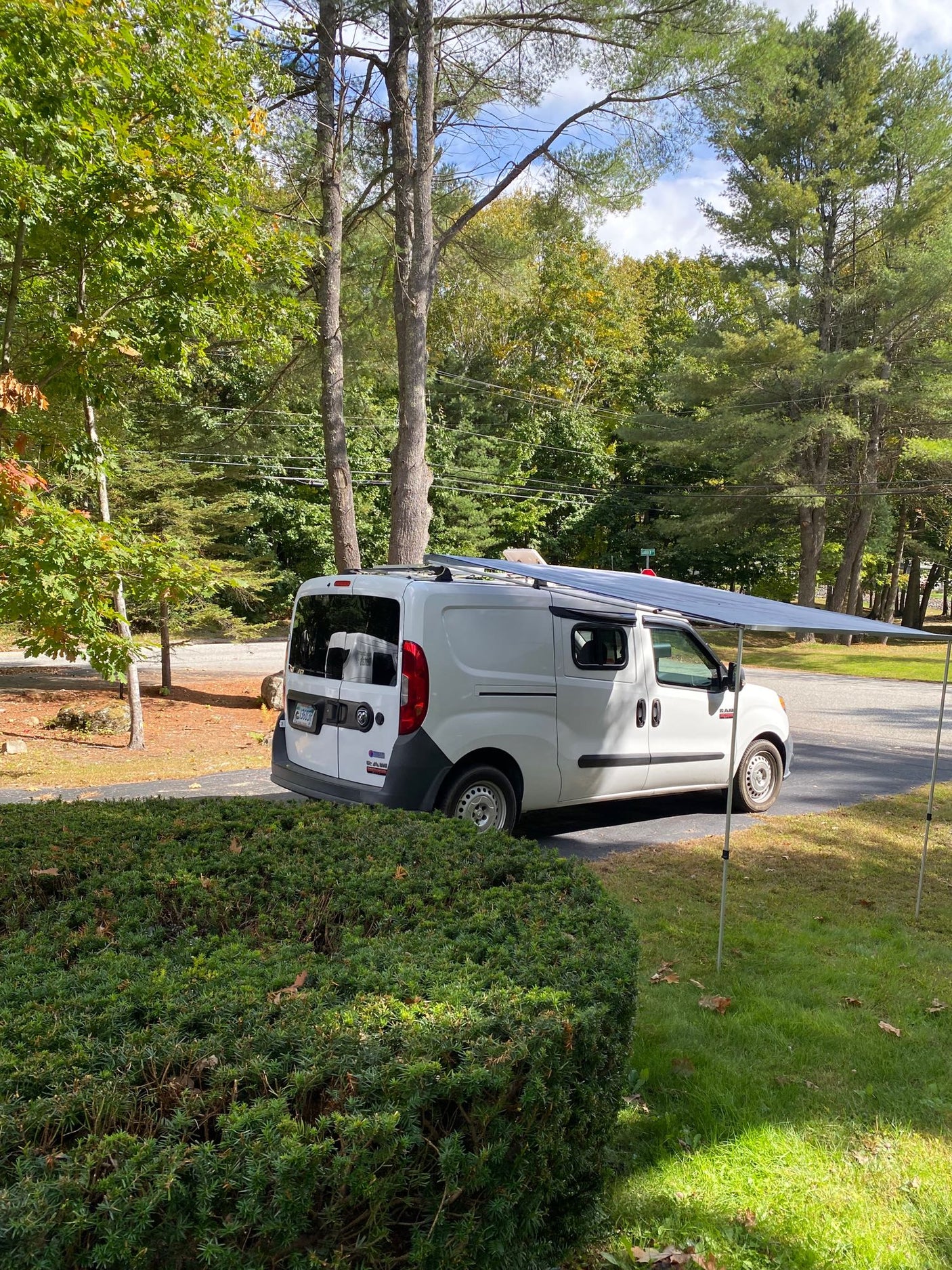 White camper van with an extended awning, perfect for an RV rental adventure in nature.