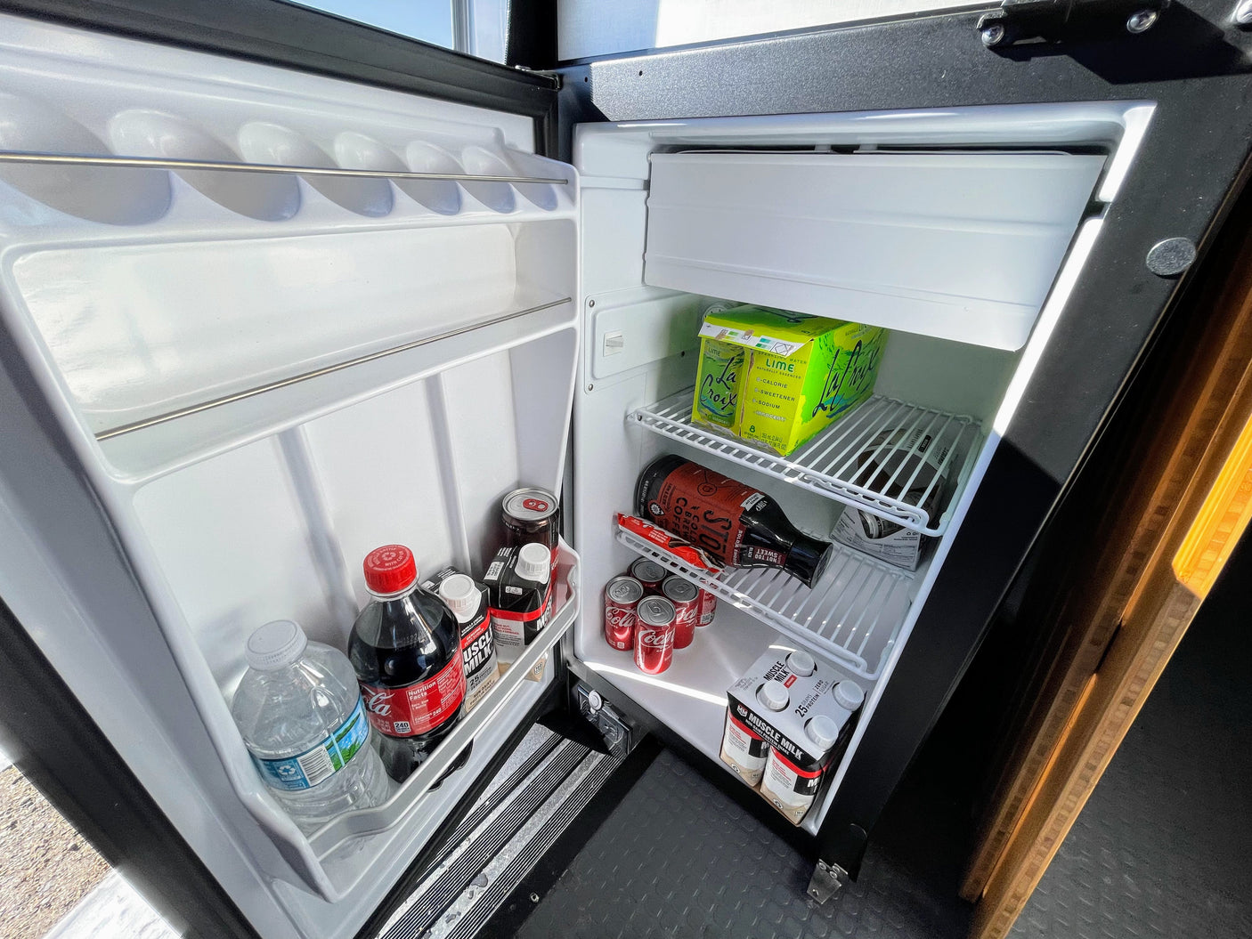 RV rental mini-fridge, neatly stocked with sparkling water, sodas, protein drinks, water, and cold brew coffee.