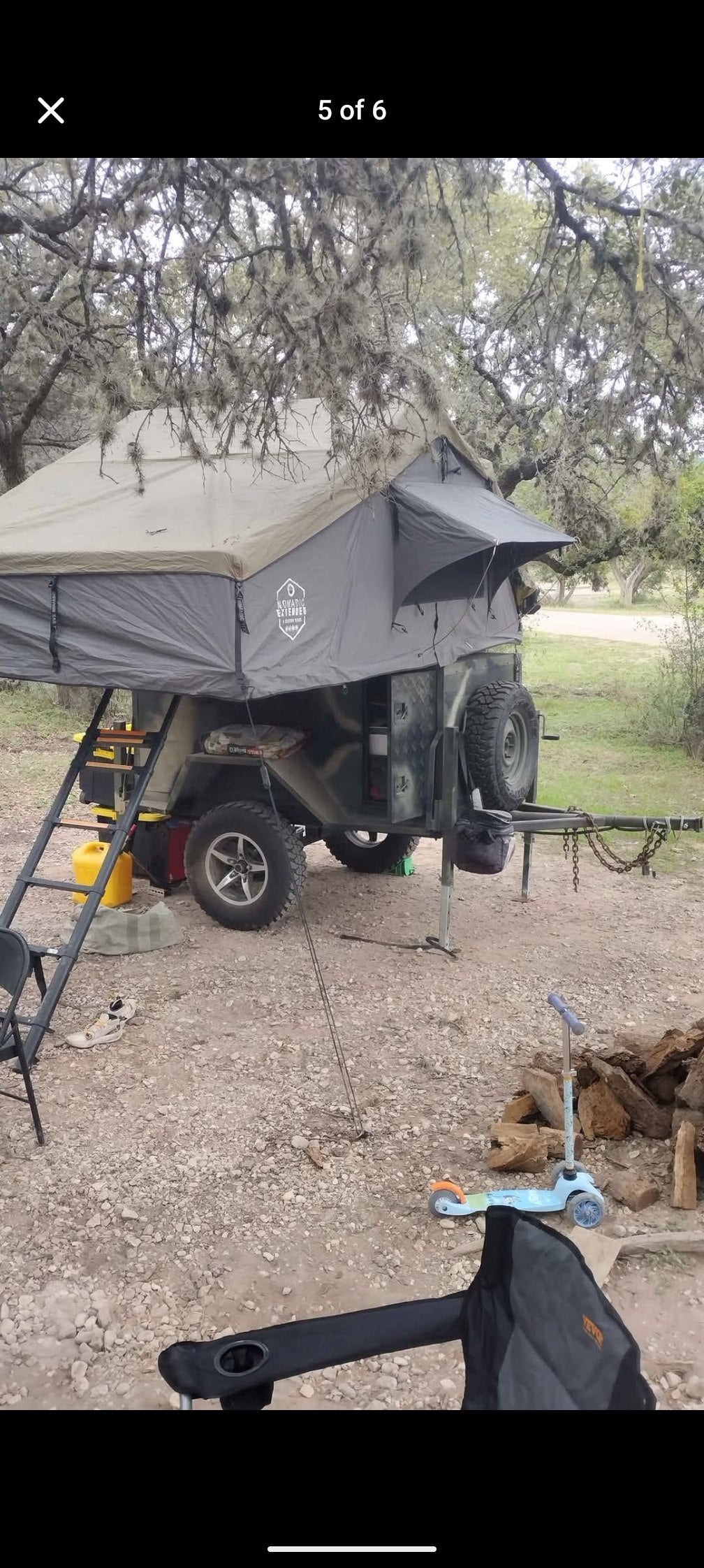 Rugged off-road trailer with a Nomadic Extended rooftop tent setup at a campsite. An alternative to an RV rental for camping.