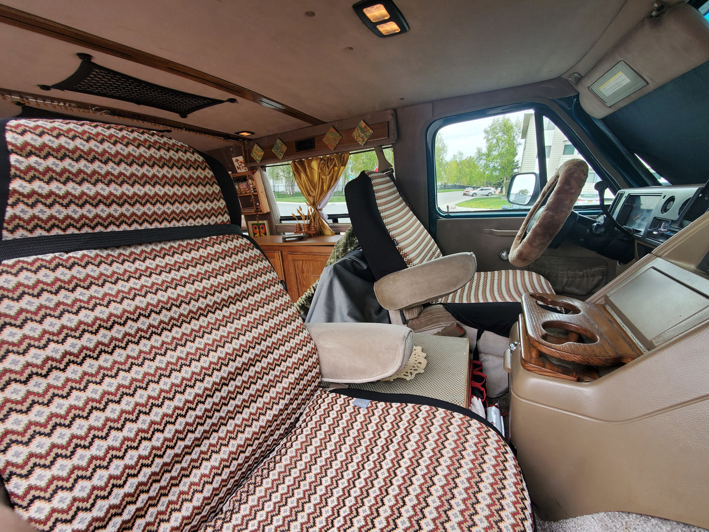 Cozy RV rental interior with zigzag patterned seats, wood console, and a clear view for your next road trip adventure.