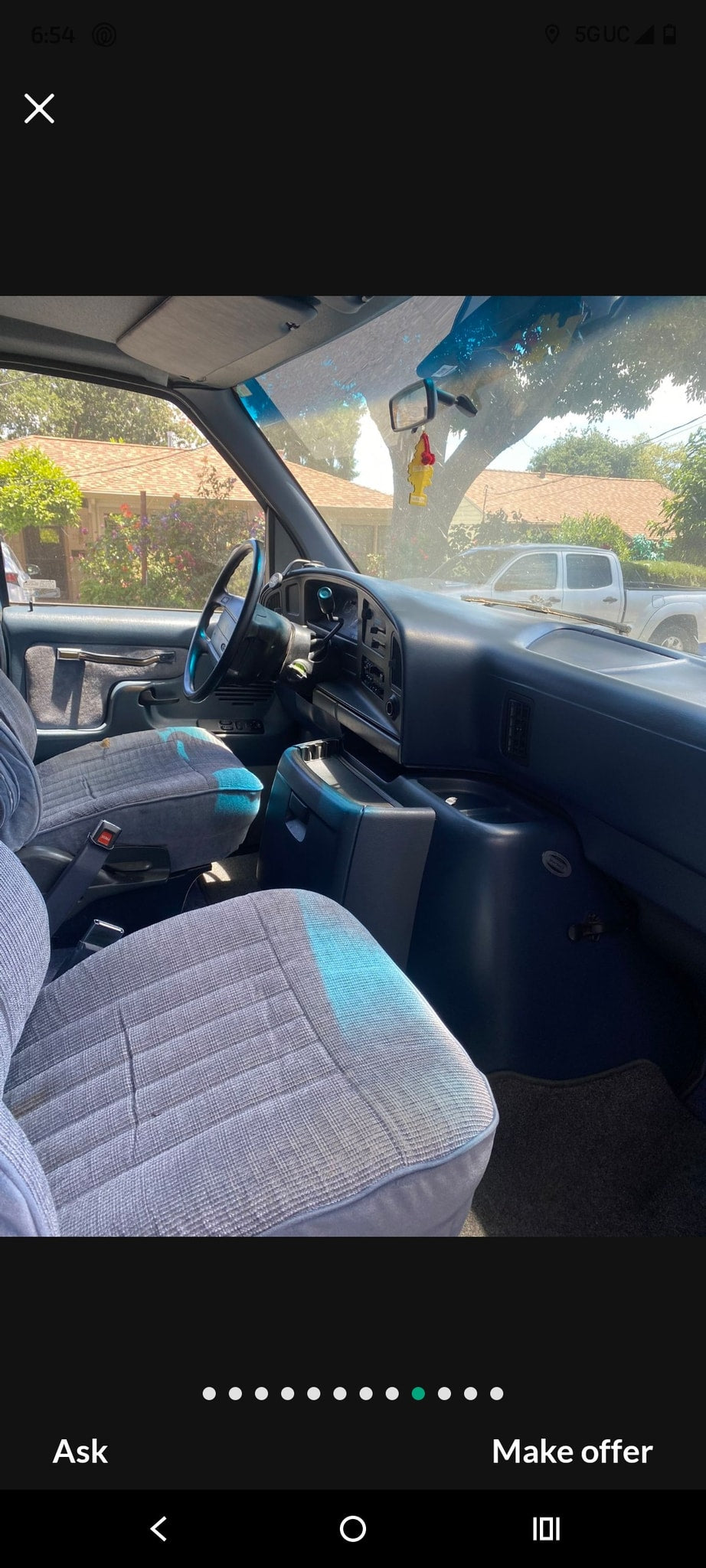 Van interior with grey seats, dashboard, and steering wheel, suitable for rv rental. A tree and truck visible outside. — photo 9