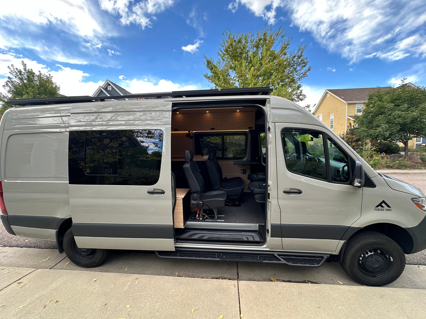 Side view of a modern, light-colored camper van with its door open, showcasing a custom-built interior. Ideal for rv rental.