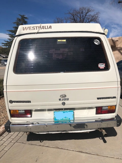 Explore New Mexico! Rear of a classic off-white VW Vanagon Westfalia pop-top camper van, perfect for your RV rental getaway.