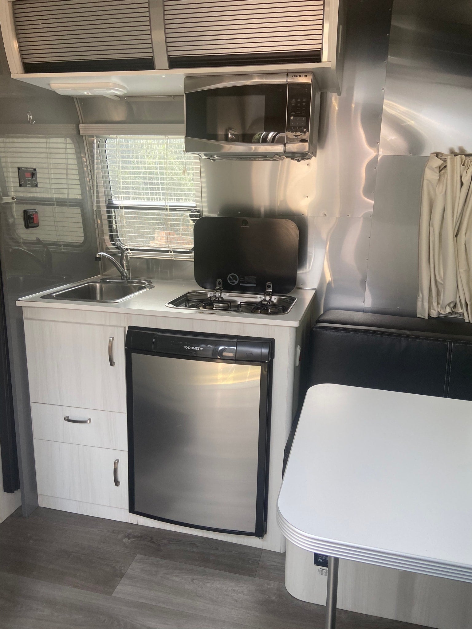 is perfectly set for dry camping on a quiet gravel lot.|Modern Airstream RV rental interior features a kitchen