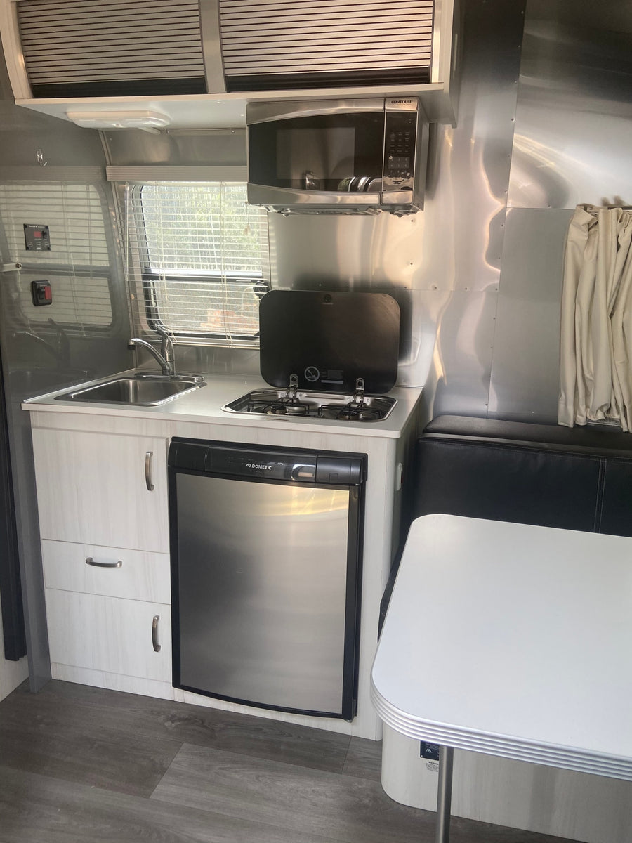 is perfectly set for dry camping on a quiet gravel lot.|Modern Airstream RV rental interior features a kitchen