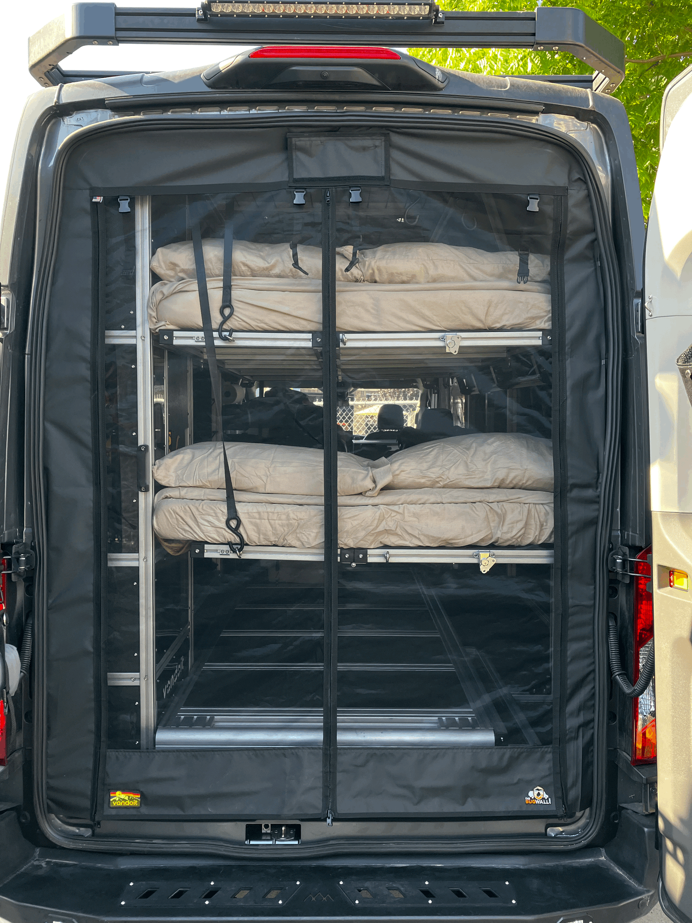 Rear of an rv rental van featuring a bug screen and interior modular shelving with rolled sleeping gear, ready for adventure.