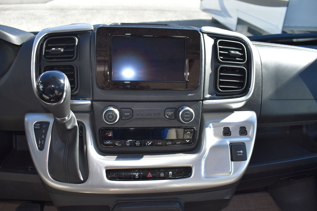 RV rental interior: Dashboard with touchscreen, climate controls, gear shifter, and multiple charging ports.