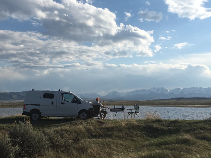 facing snow-capped mountains under blue sky. Ideal RV rental for scenic adventures.|Relaxing by the water in an RV rental