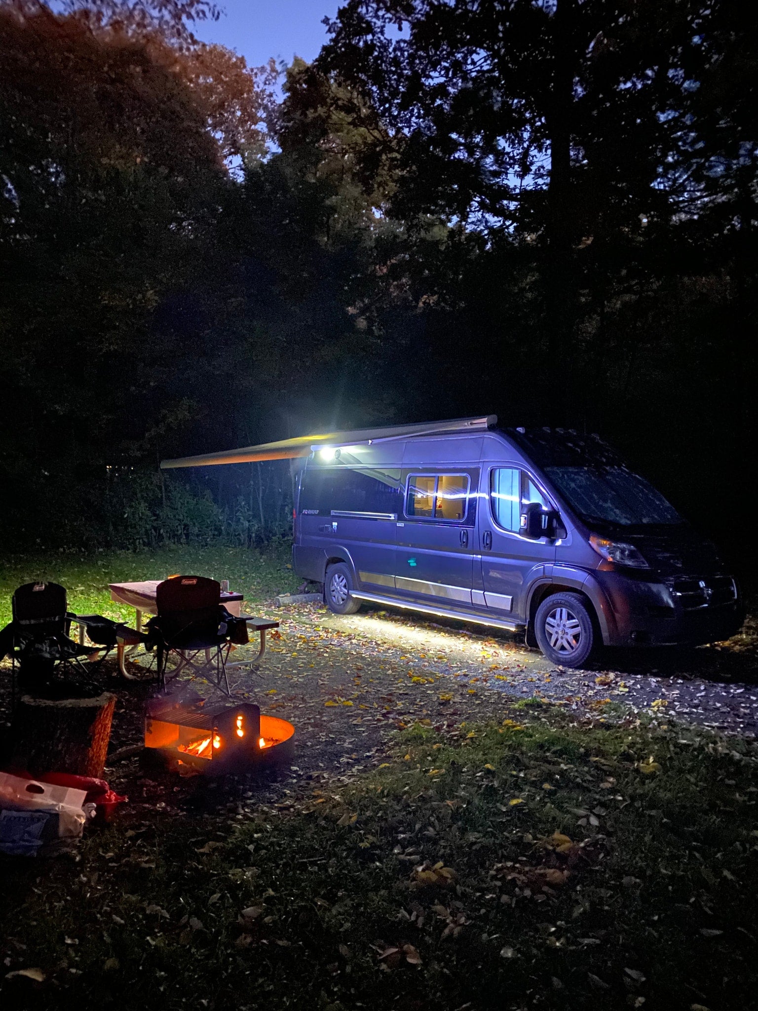 and fire pit under colorful trees.|Cozy night camping with an RV rental: warm campfire