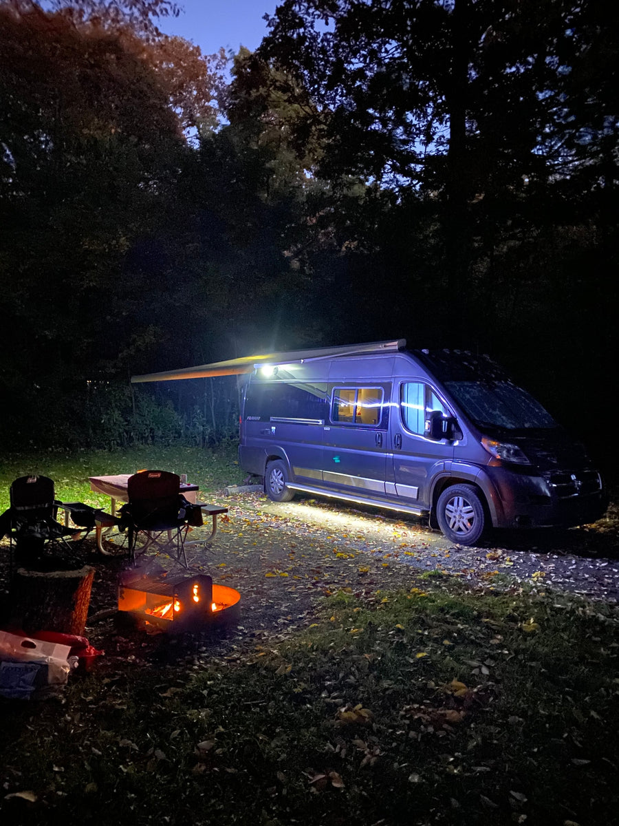 and fire pit under colorful trees.|Cozy night camping with an RV rental: warm campfire