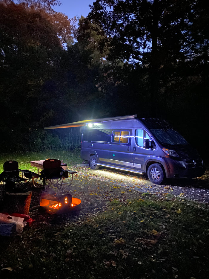 and fire pit under colorful trees.|Cozy night camping with an RV rental: warm campfire