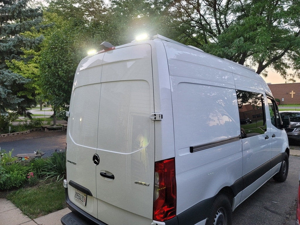 and a compact fridge.|Interior of a grey rv rental camper van with a convertible bed
