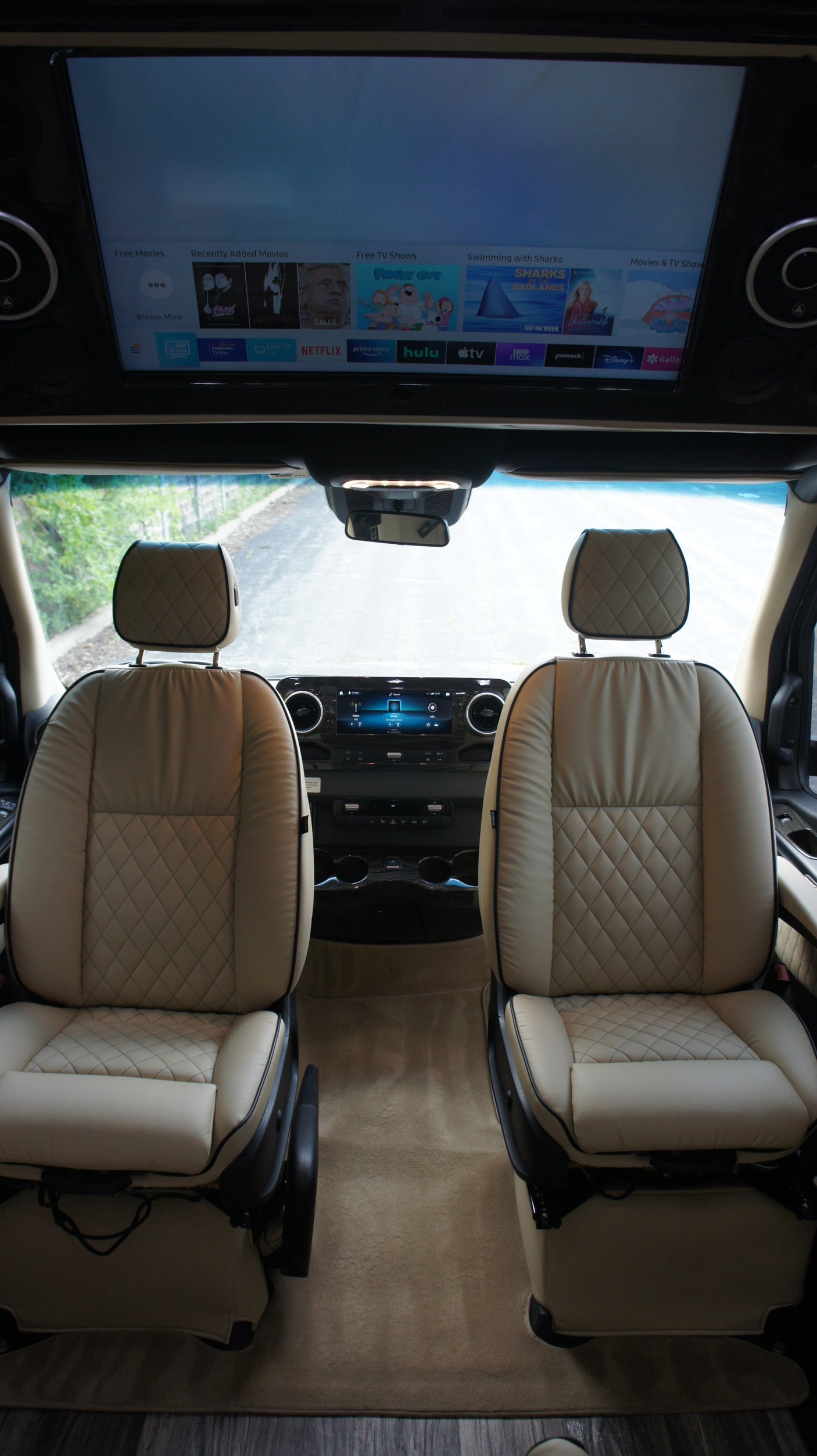 Luxurious RV rental interior with comfortable quilted seats and a large media screen for streaming entertainment.