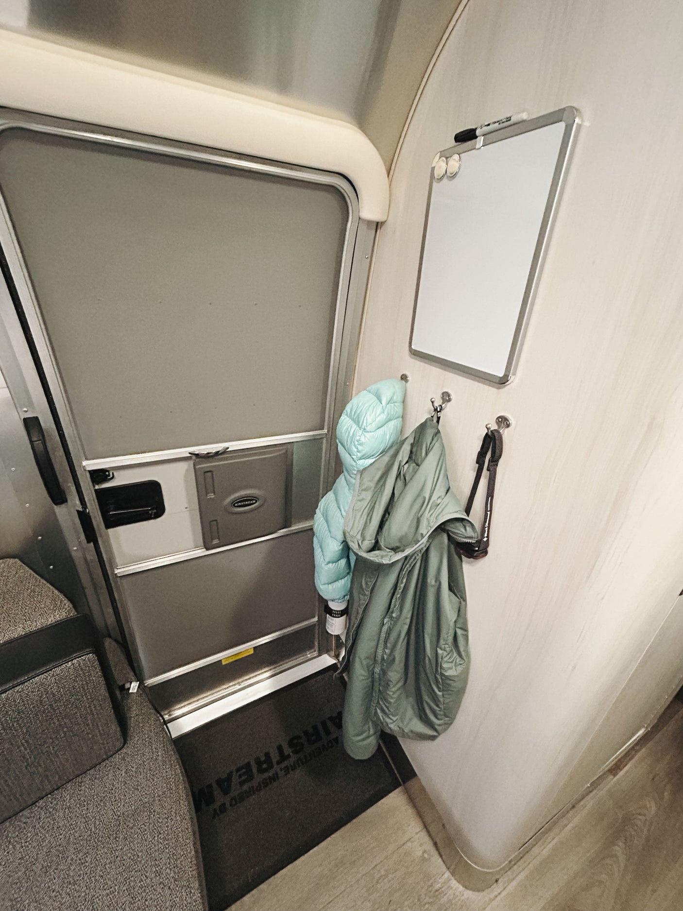 Airstream rv rental interior: entrance door, coats on hooks, magnetic whiteboard, and welcome mat.