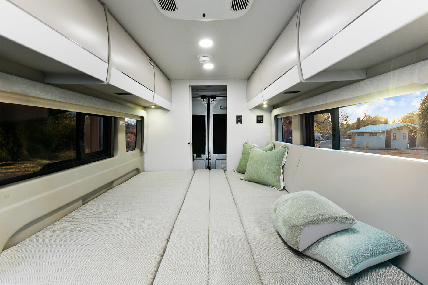 Spacious camper van interior for your next rv rental adventure. Features comfortable bed/seating and overhead storage.