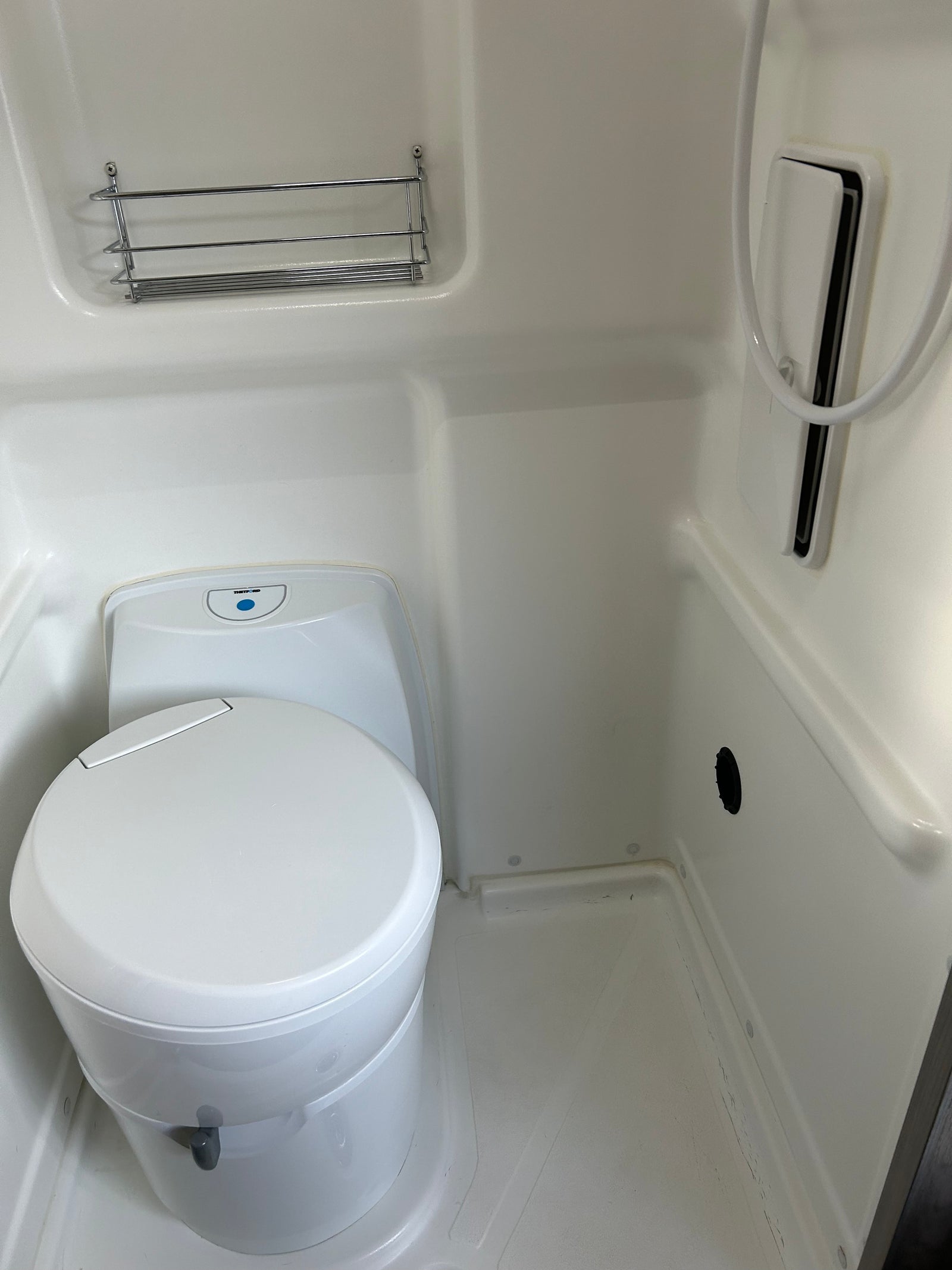 RV rental wet bath: Thetford toilet, shower, and chrome shelf. A compact and functional space.