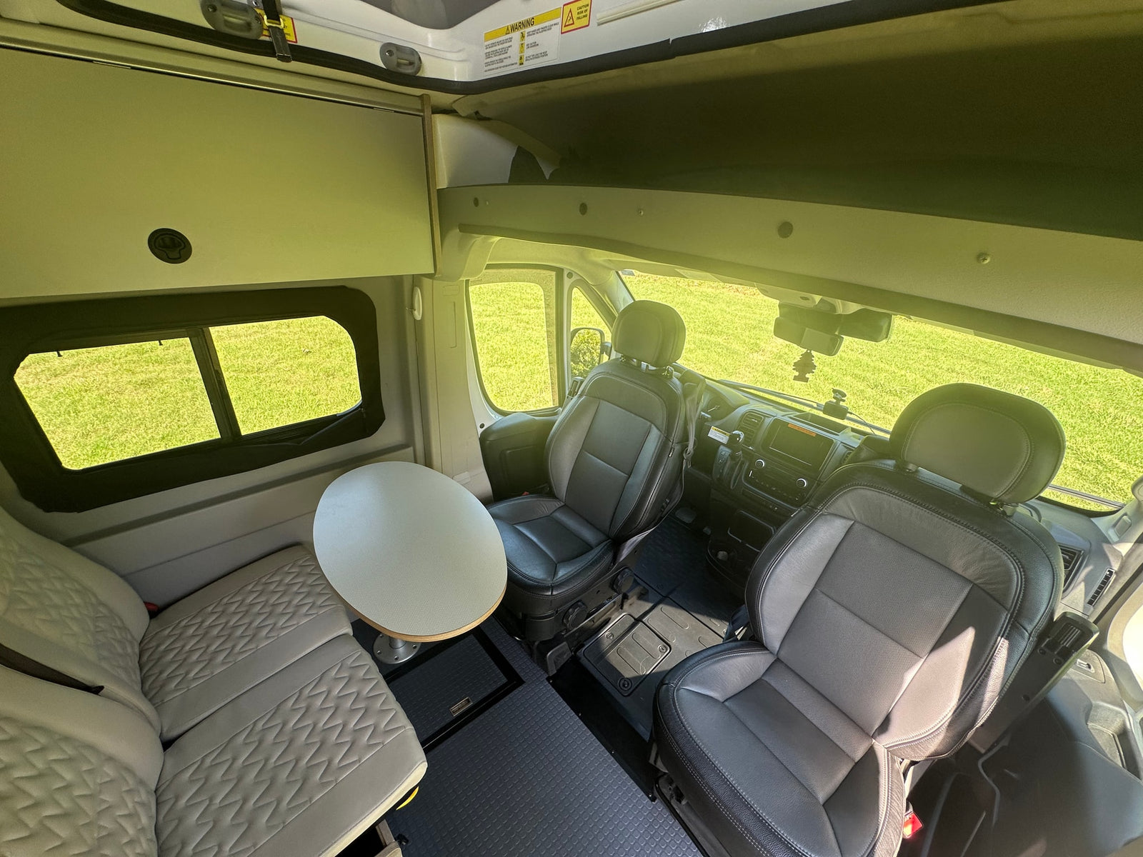 and extended pop-top on grass.|White pop-top camper van for your next RV rental adventure. Parked on grass with trees under a blue sky.|Front view of a white Ram ProMaster pop-top camper van for rv rental