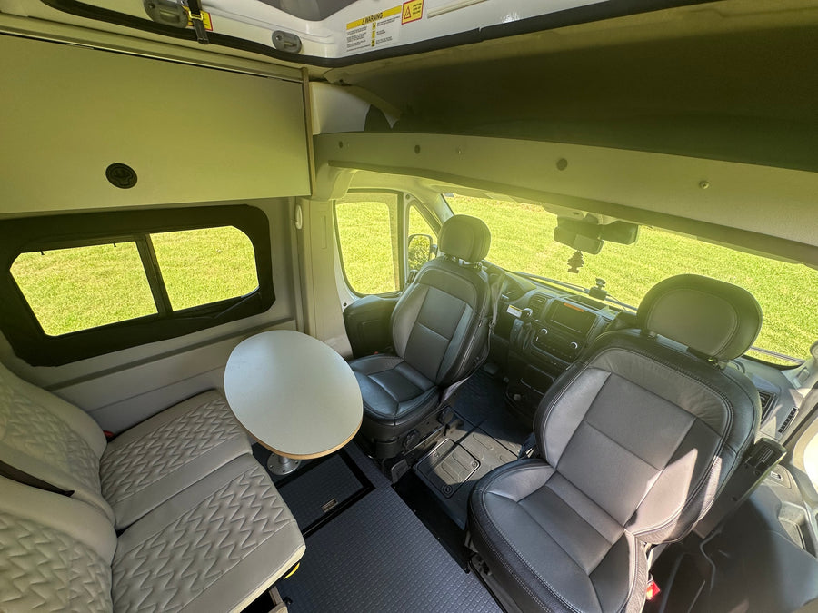 and extended pop-top on grass.|White pop-top camper van for your next RV rental adventure. Parked on grass with trees under a blue sky.|Front view of a white Ram ProMaster pop-top camper van for rv rental