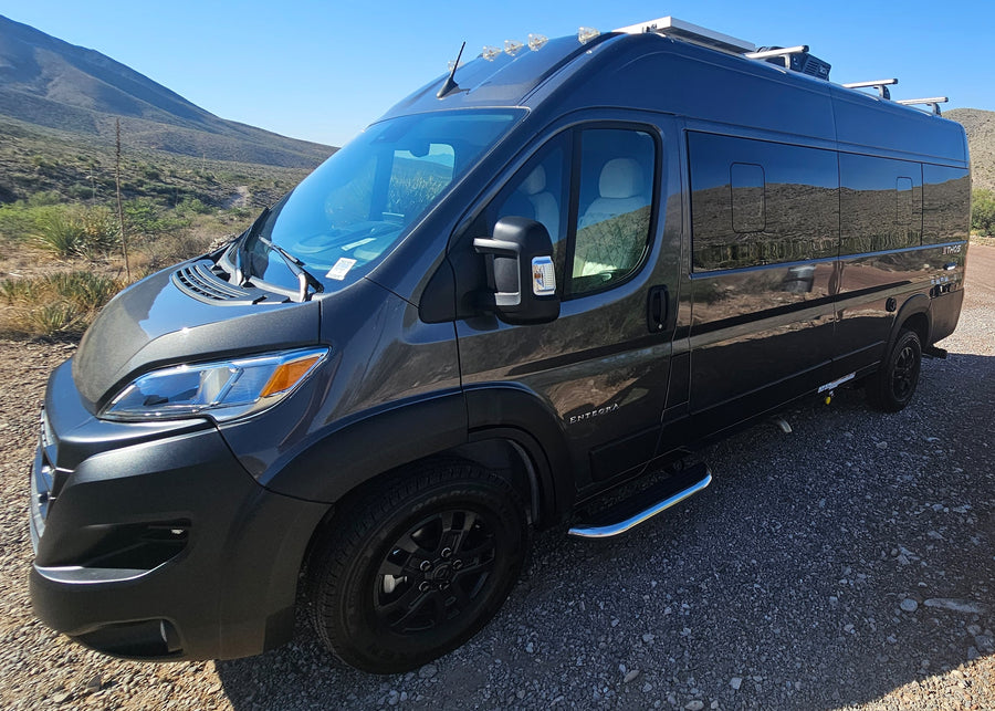 reflecting mountains.|Grey Ethos RV rental's utility panel and rear tire visible
