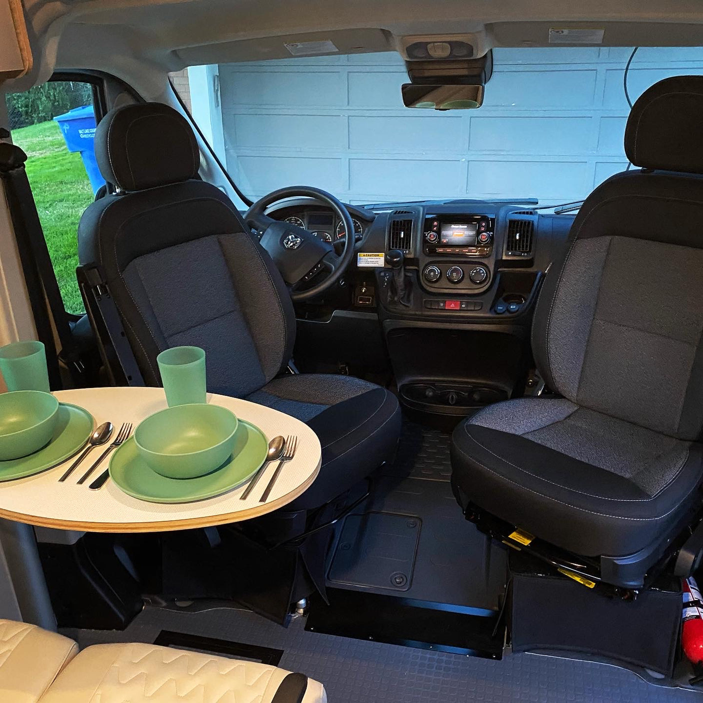 Compact rv rental interior: swivel front seats converted to a dining area with a set table, ready for travel meals.