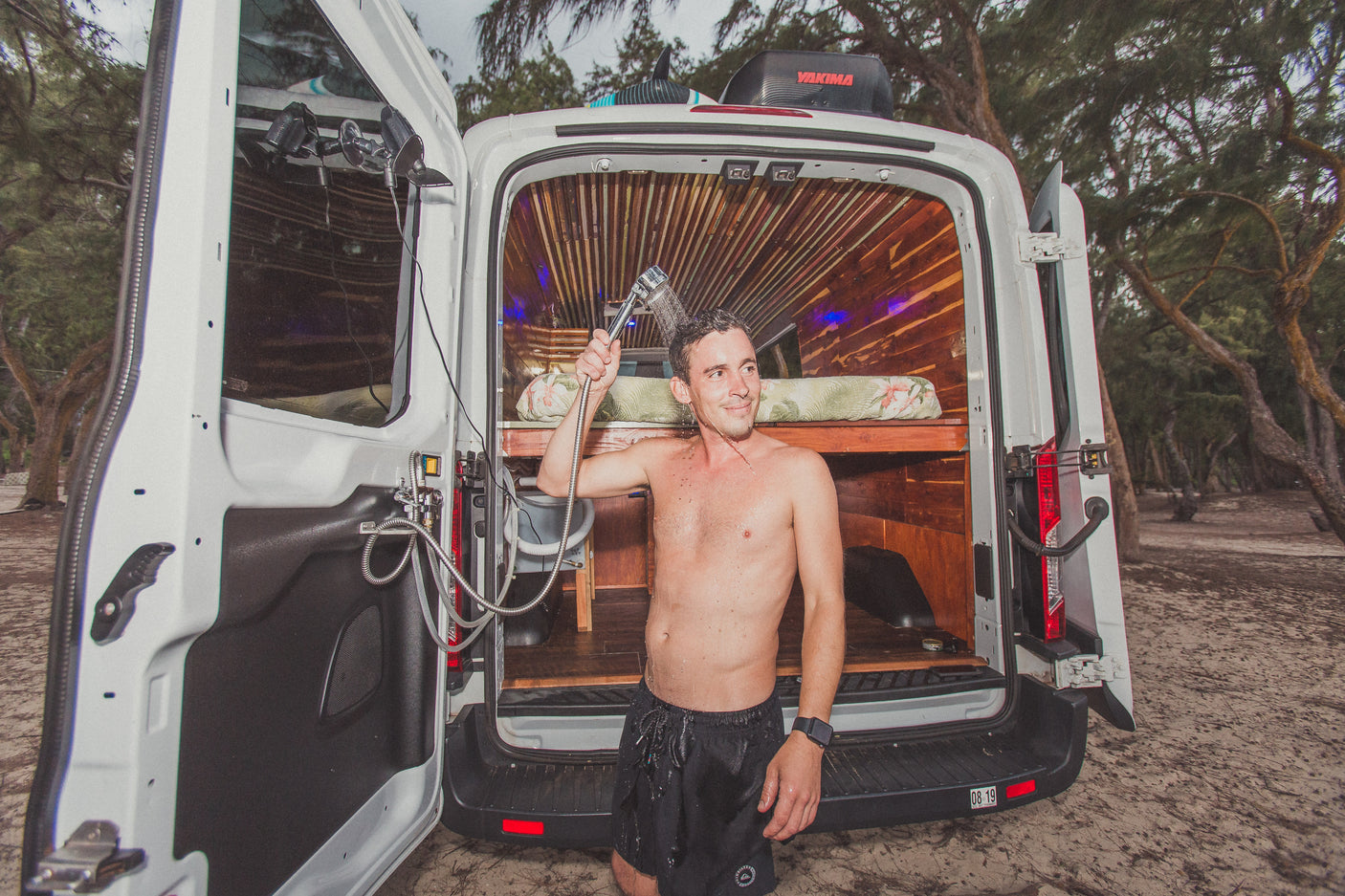 Enjoy an outdoor shower with your RV rental! This customized camper van offers mobile living comfort amidst nature.