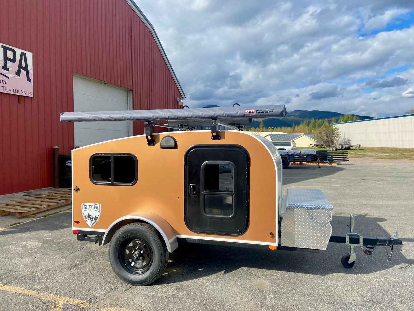 Compact tan Sherpa teardrop trailer with ARB awning, perfect for RV rental camping trips.