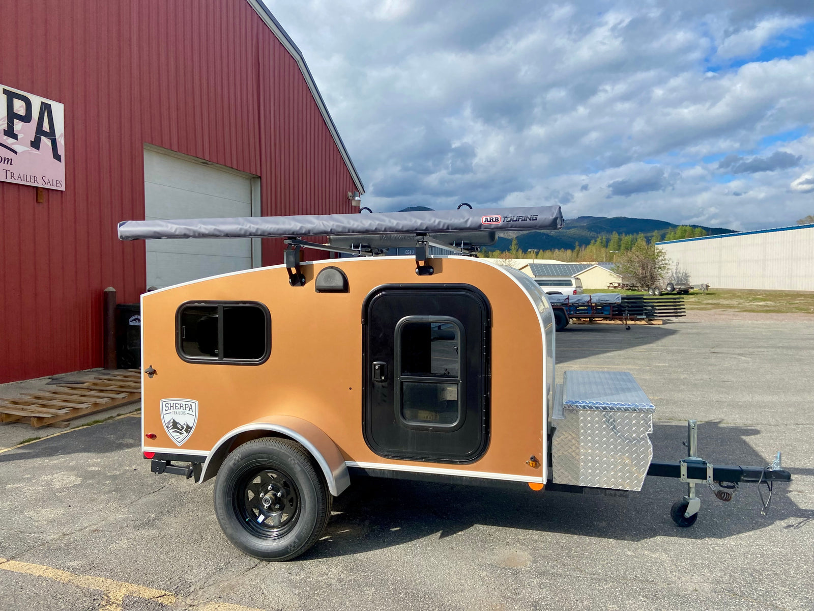 Compact tan Sherpa teardrop trailer with ARB awning, perfect for RV rental camping trips.
