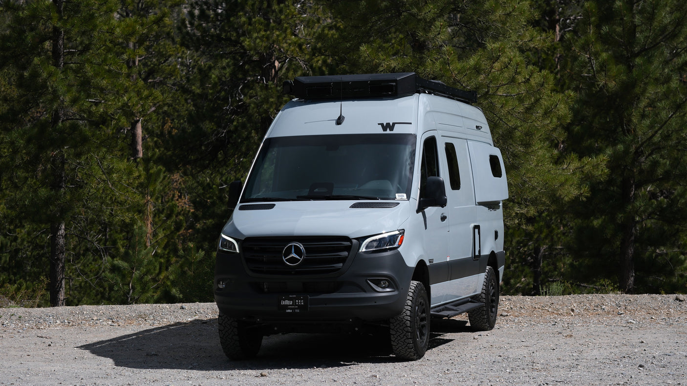 Adventure-ready Mercedes-Benz Sprinter RV rental on a gravel forest road, ideal for outdoor travel.