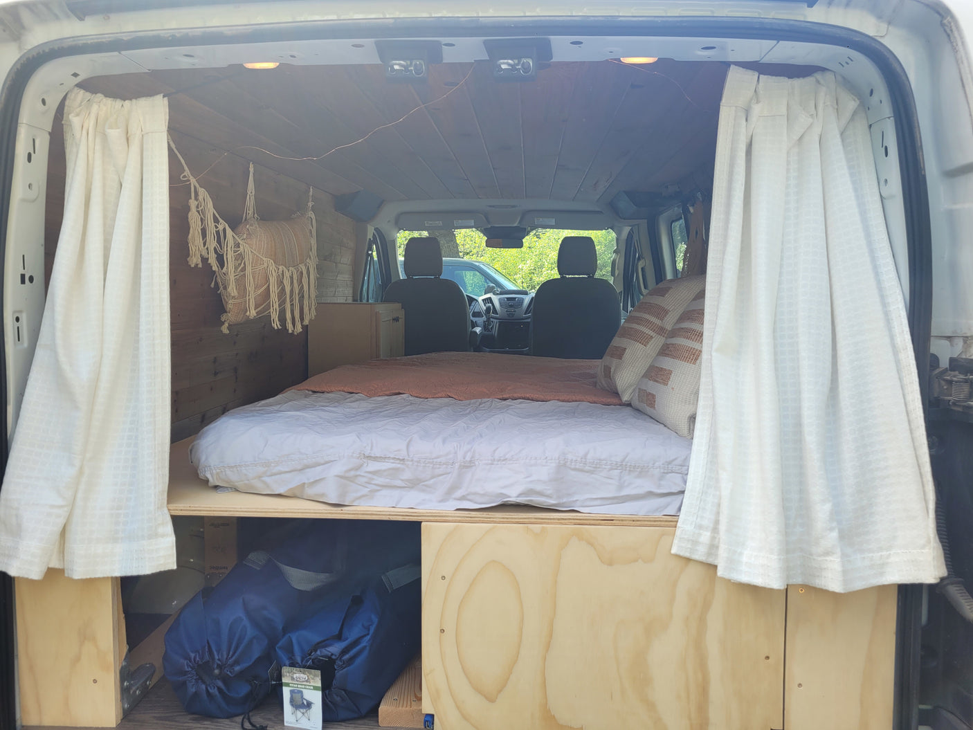 Cozy RV rental interior featuring a comfortable bed, wood paneling, and ample storage for your next adventure.