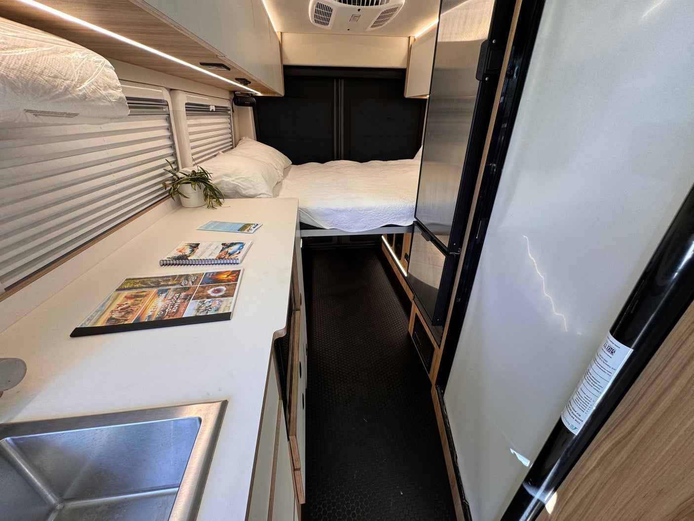 Experience comfort in this RV rental's interior, featuring a bed, kitchenette with sink, and a retractable shower door.