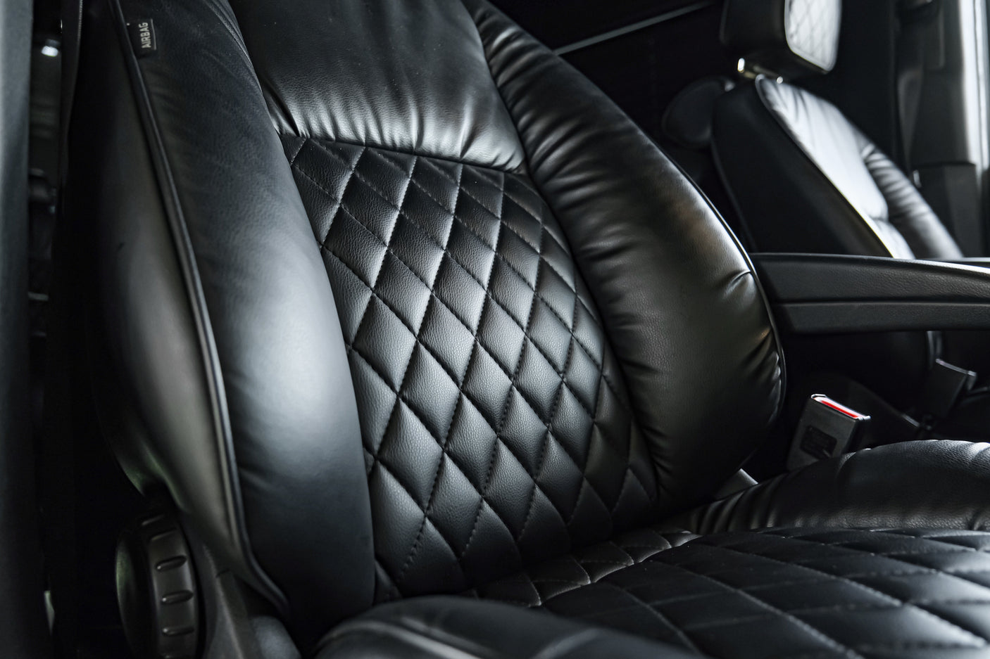 Close-up of a luxurious black leather seat with diamond stitching and an "AIRBAG" label, typical of a high-end RV rental.