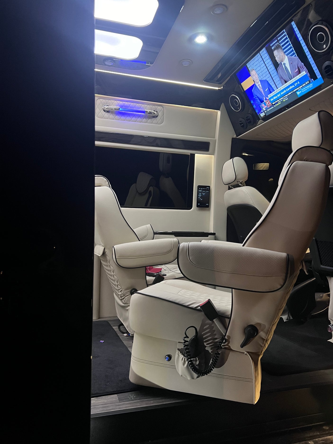 Luxury RV rental interior with comfy captain's chairs, TV, and ambient lighting, perfect for travel.
