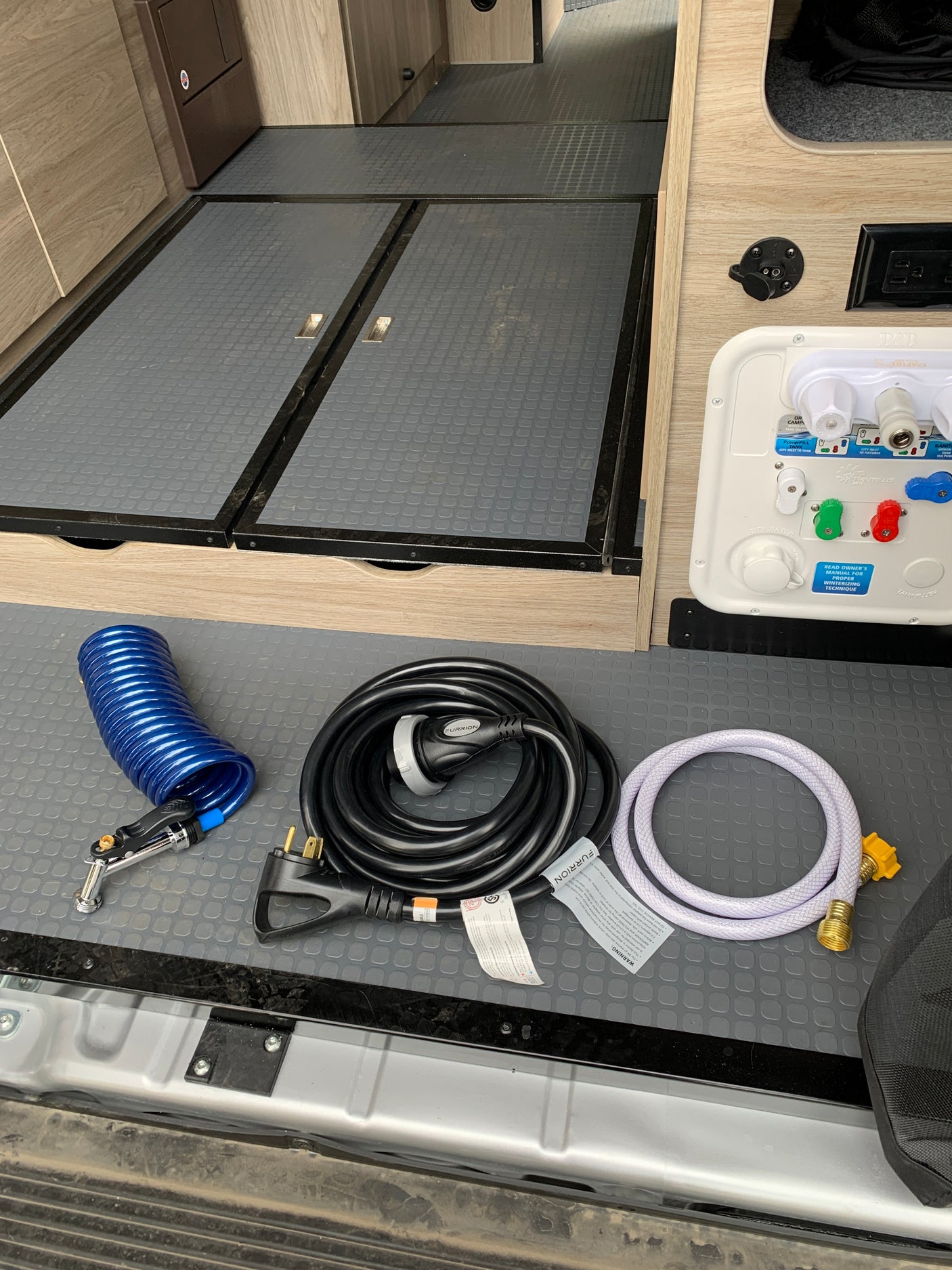 RV rental ready! Essential utilities and accessories for RV camping, including hoses, shore power cord, and water connection panel.