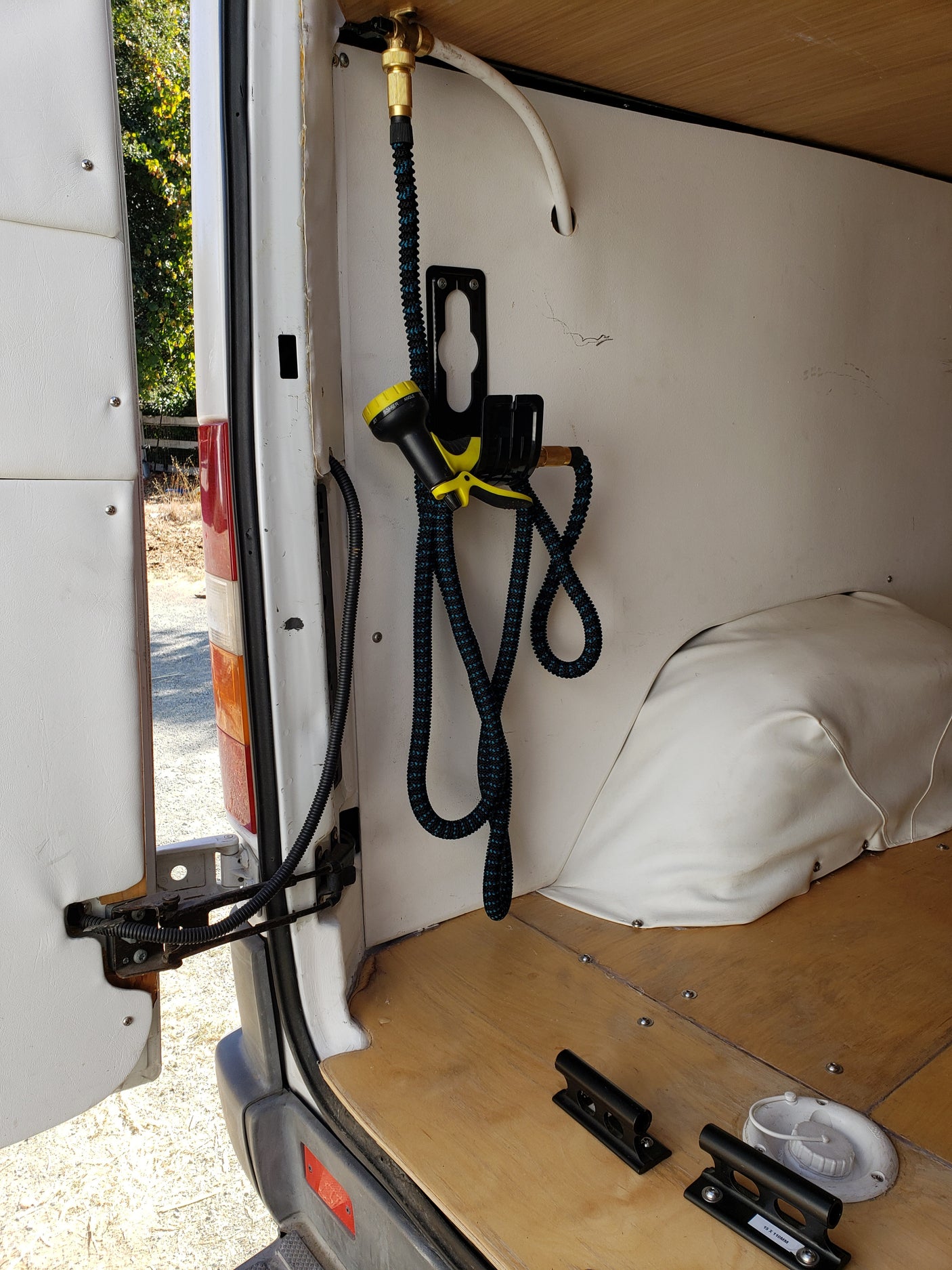 RV rental van's outdoor shower, water system, and bike mounts inside rear cargo area.