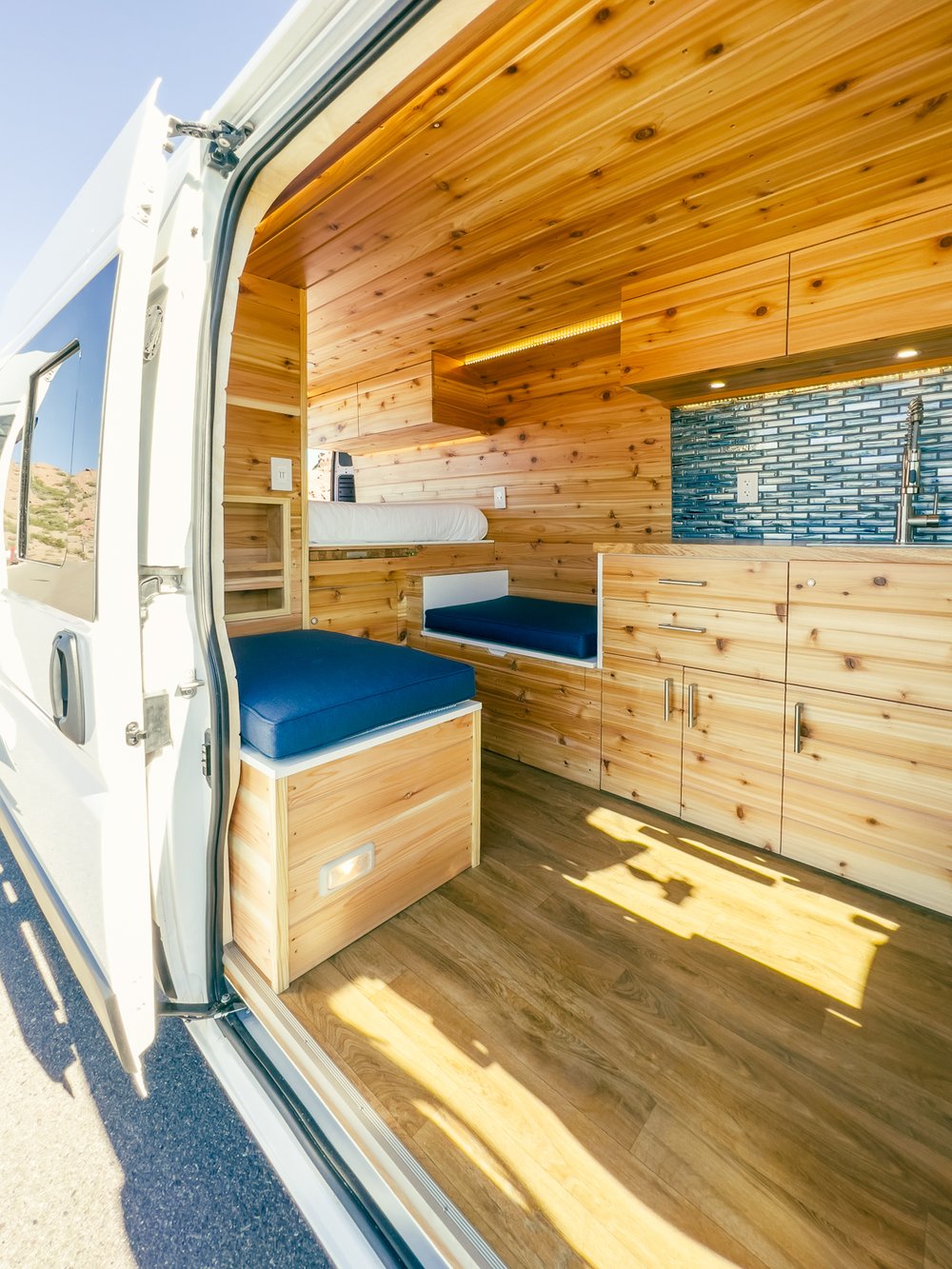 perfect for adventure.|RV rental: Comfy bed in wood-paneled van interior
