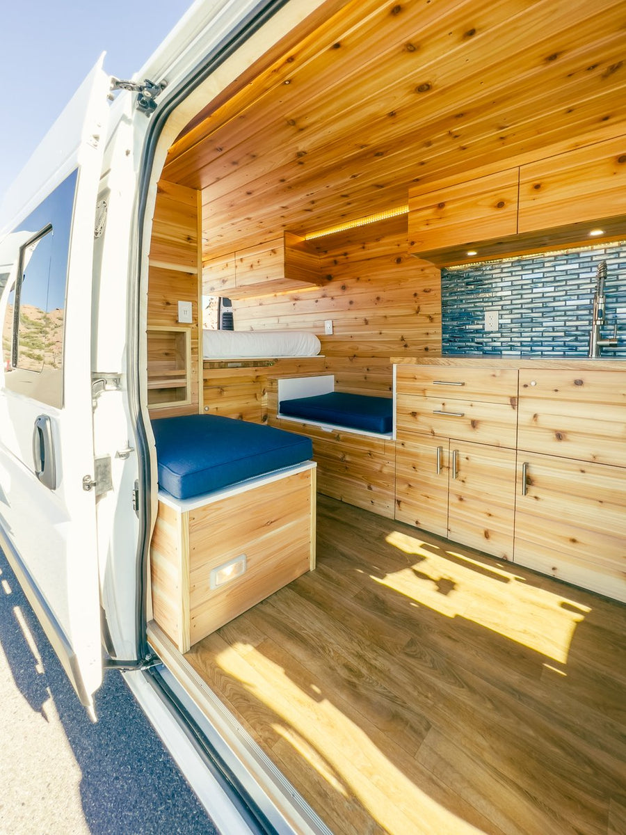 perfect for adventure.|RV rental: Comfy bed in wood-paneled van interior