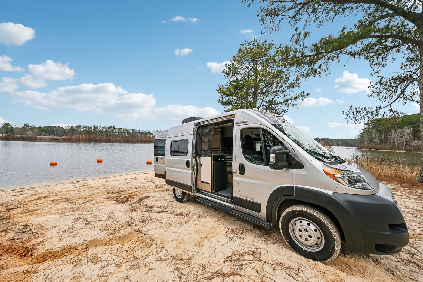 and a modular slat bed system. Ideal for travel.|Rv rental: open camper van doors frame a picturesque lake and sandy beach