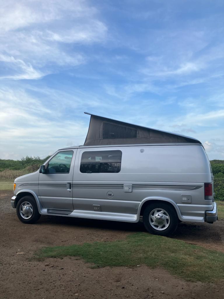Silver Ford E-series pop-top RV rental van parked. Perfect for your next outdoor adventure.