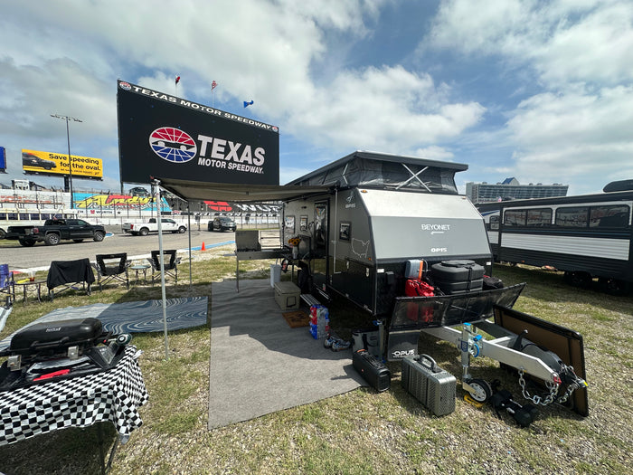 and comfortable seating.|Experience race day camping! This equipped off-road RV setup at Texas Motor Speedway is perfect for an RV rental adventure.|Cozy RV rental interior featuring a modern pop-up camper design with a bed