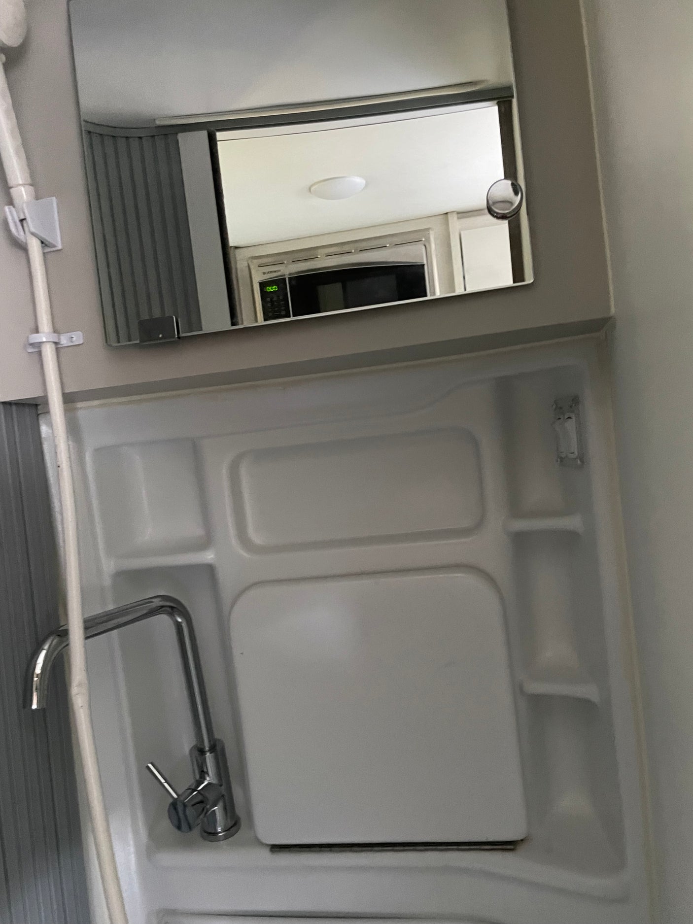 RV rental: A compact wet bath with sink, shower, and a mirror reflecting the microwave in the living area.