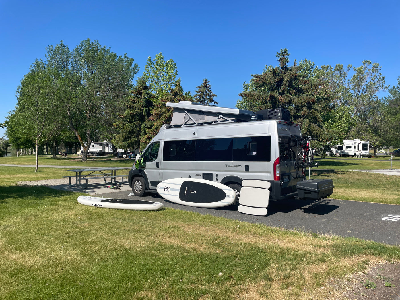 This Thor Tellaro RV rental is perfectly set up at a campground. Paddleboards and bikes are ready for water and trail adventures.