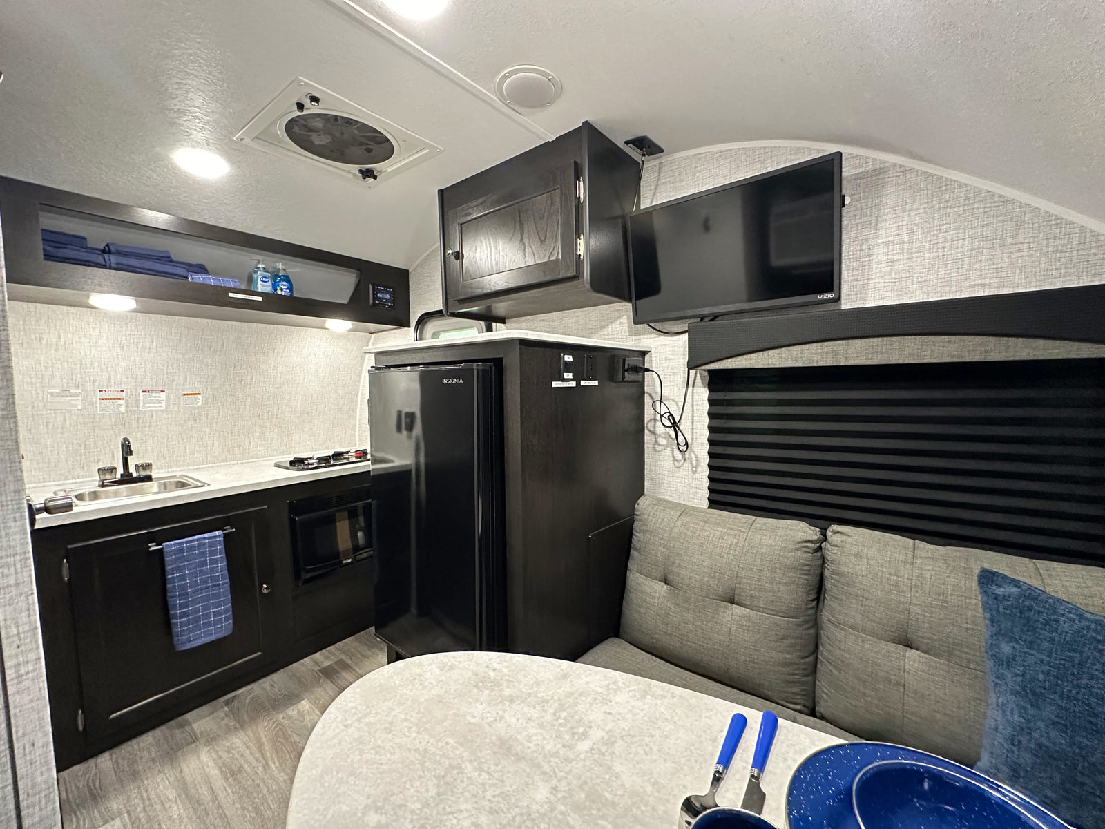 Inside an **RV rental**: a cozy kitchen with sink, stove, fridge, plus dining and TV area. Perfect for trips.