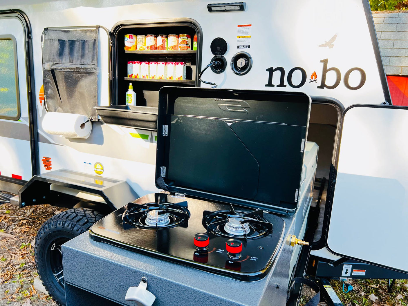 and an e-bike is set up for outdoor travel.|This rv rental features a camper trailer with a deployed rooftop tent