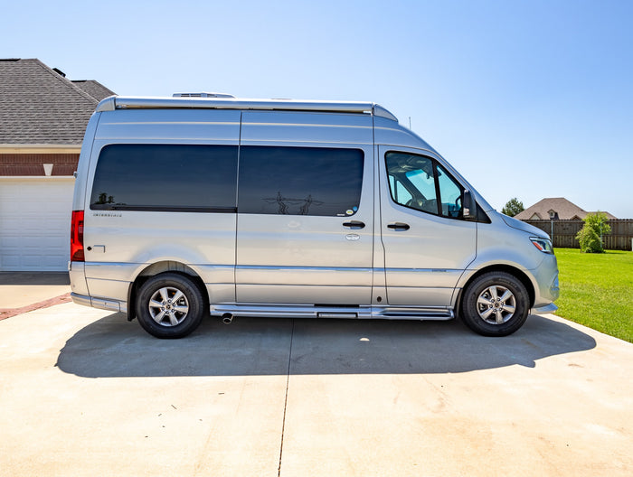 parked on a sunny driveway.|This silver Airstream Interstate RV rental