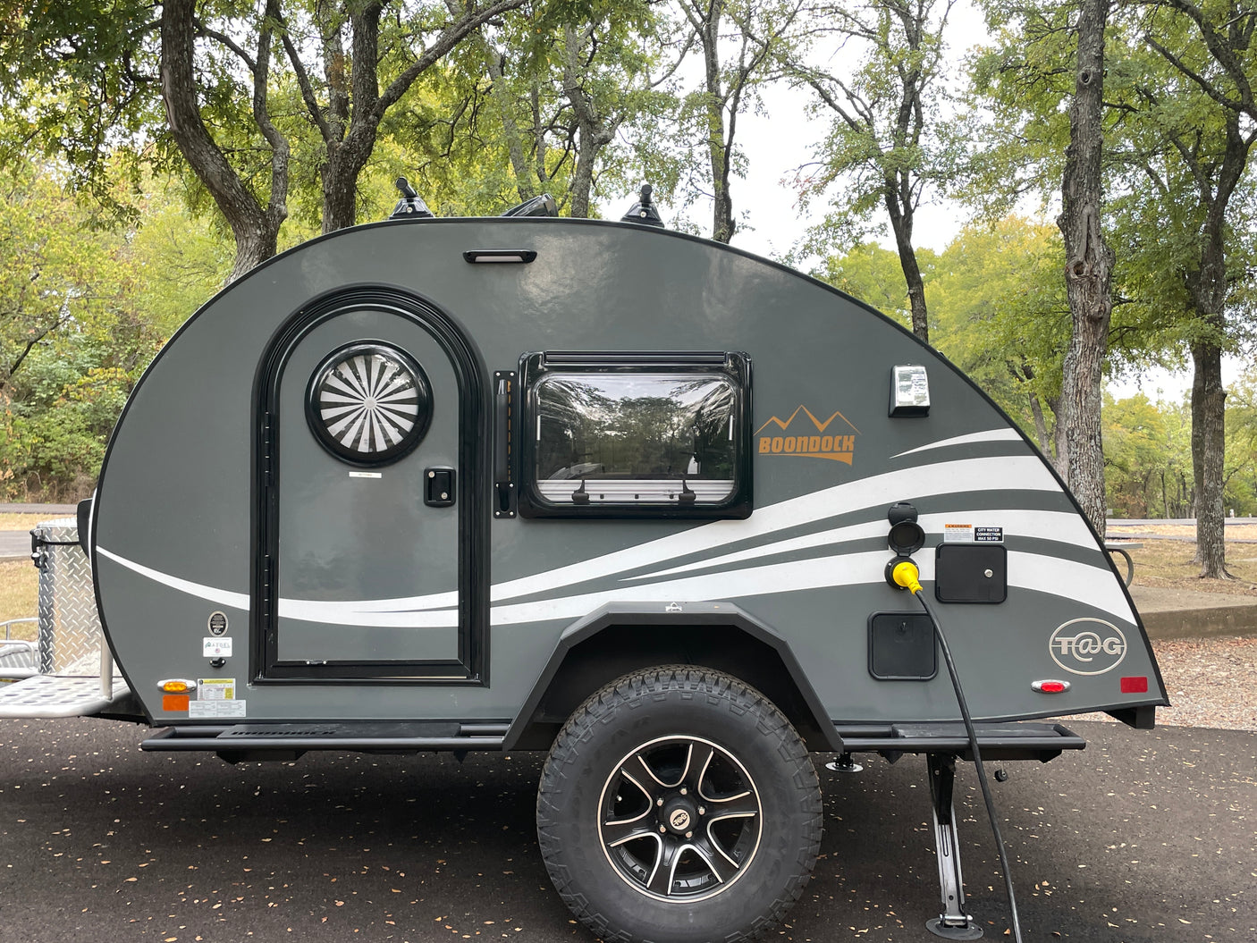 Gray Boondock teardrop **rv rental** parked at a campsite, hooked to power. Ideal for outdoor adventures and travel.