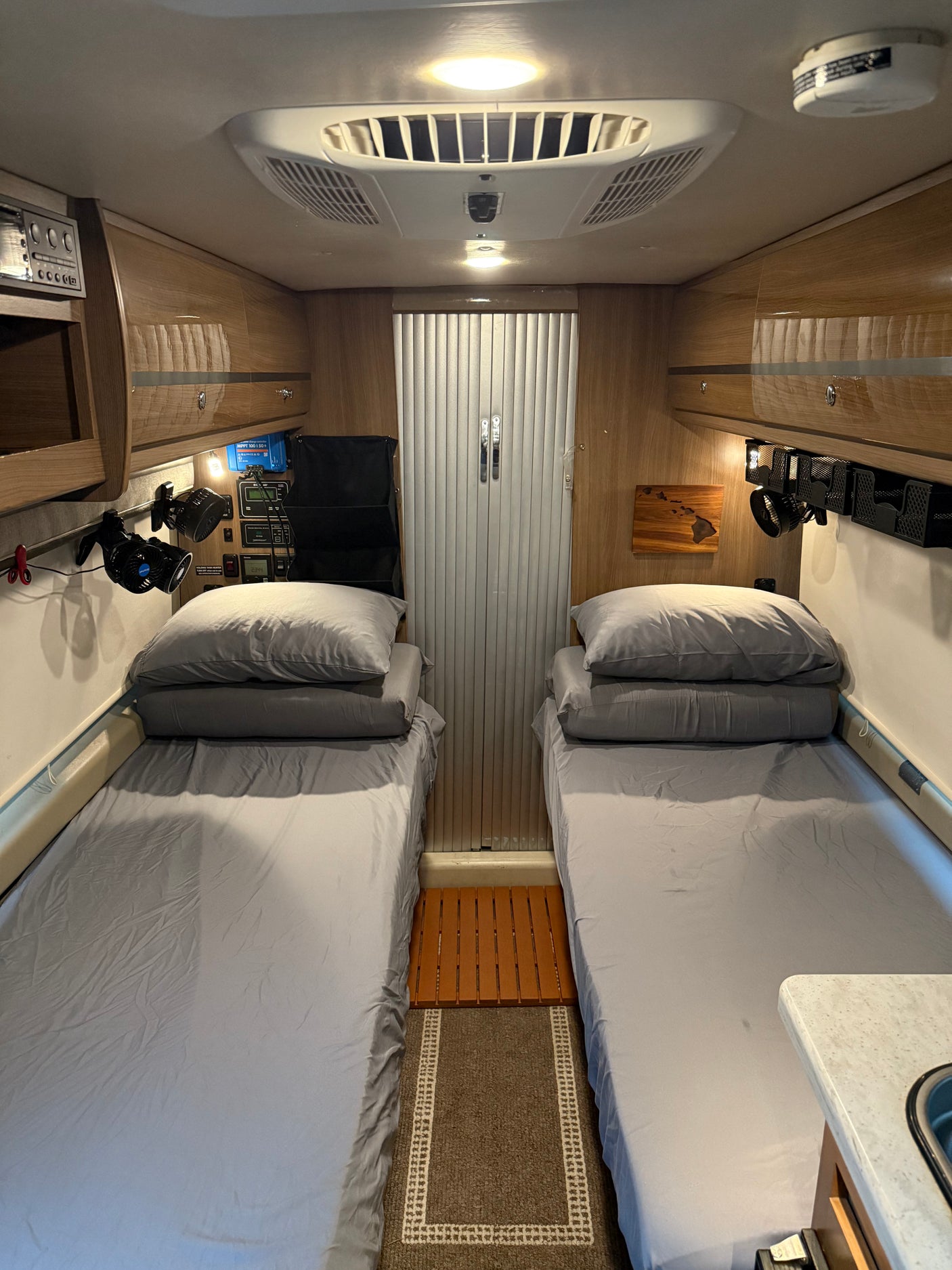 Comfortable RV rental interior shows two beds, overhead storage, AC, and a control panel for an enjoyable journey.
