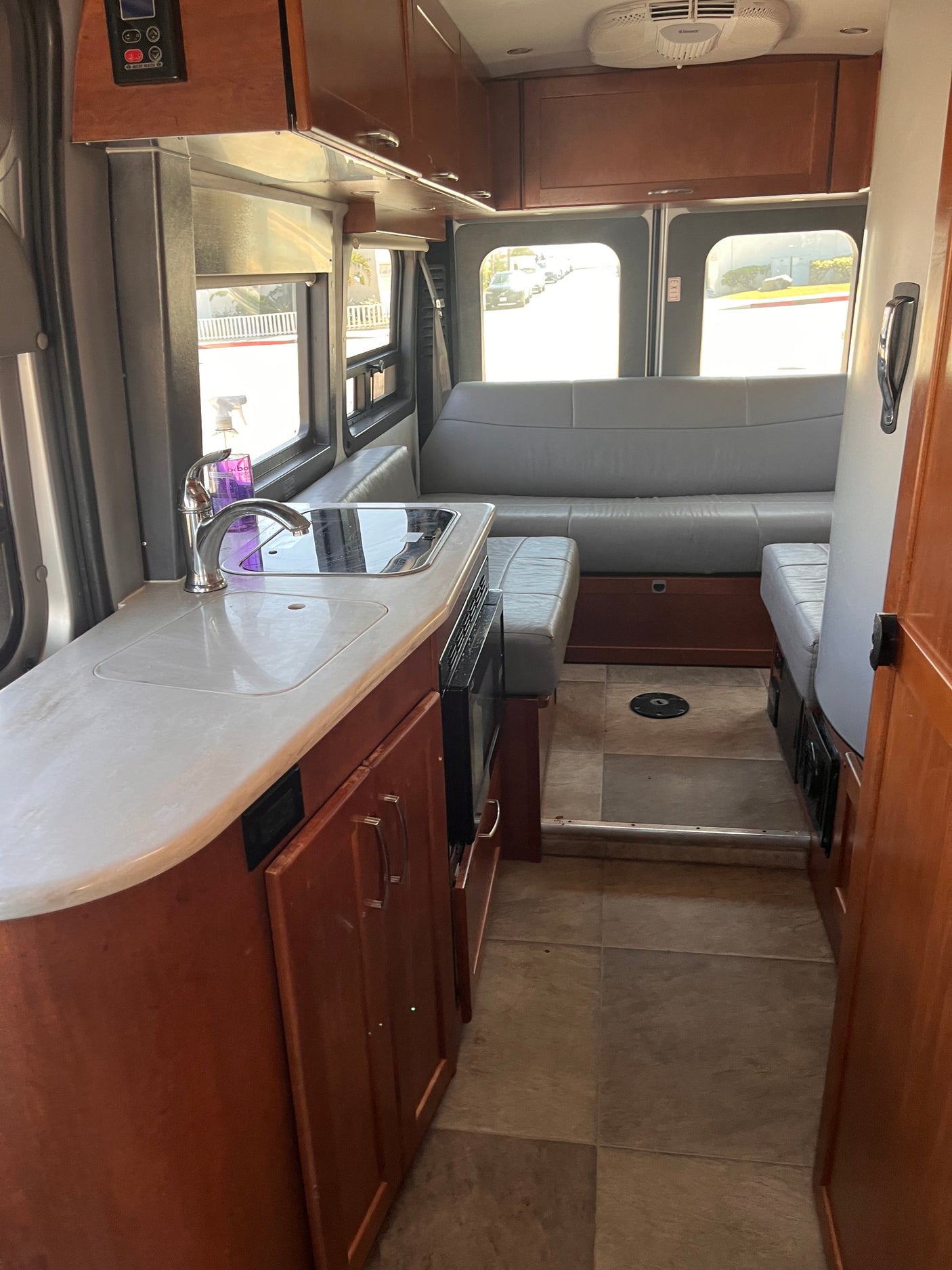 Inside this RV rental: a well-equipped kitchen (sink, stovetop, microwave) and comfortable gray sofa seating area.