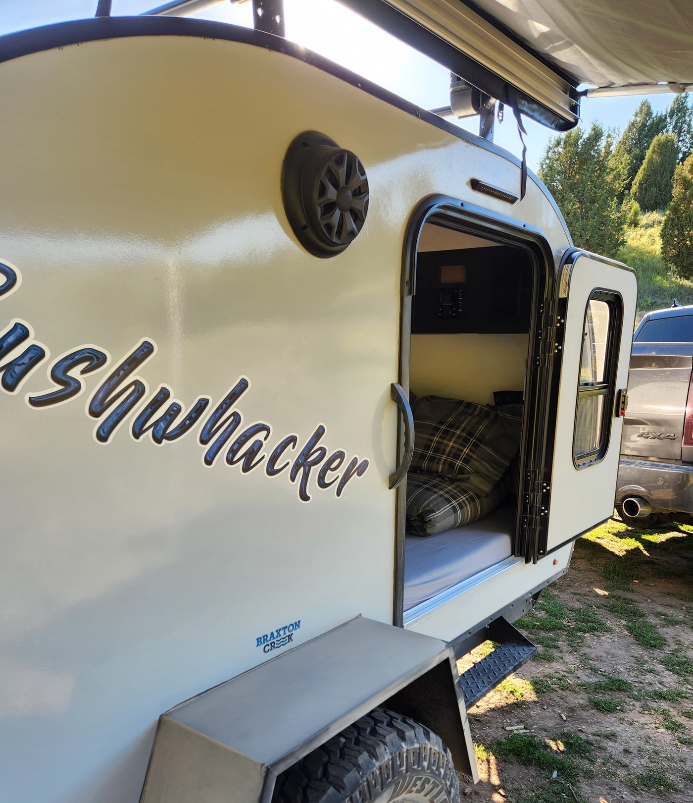 Bushwhacker teardrop RV rental with open door, showing bed & pillows. Perfect for off-road camping adventures. — photo 11