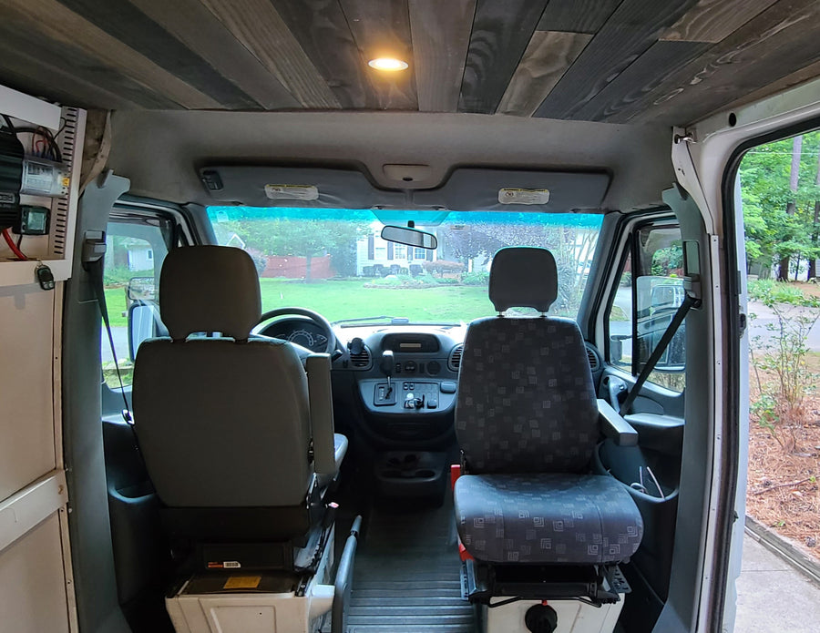 Inside an RV rental's front cabin: custom wood ceiling, comfortable front seats, and dashboard, ready for journeys.