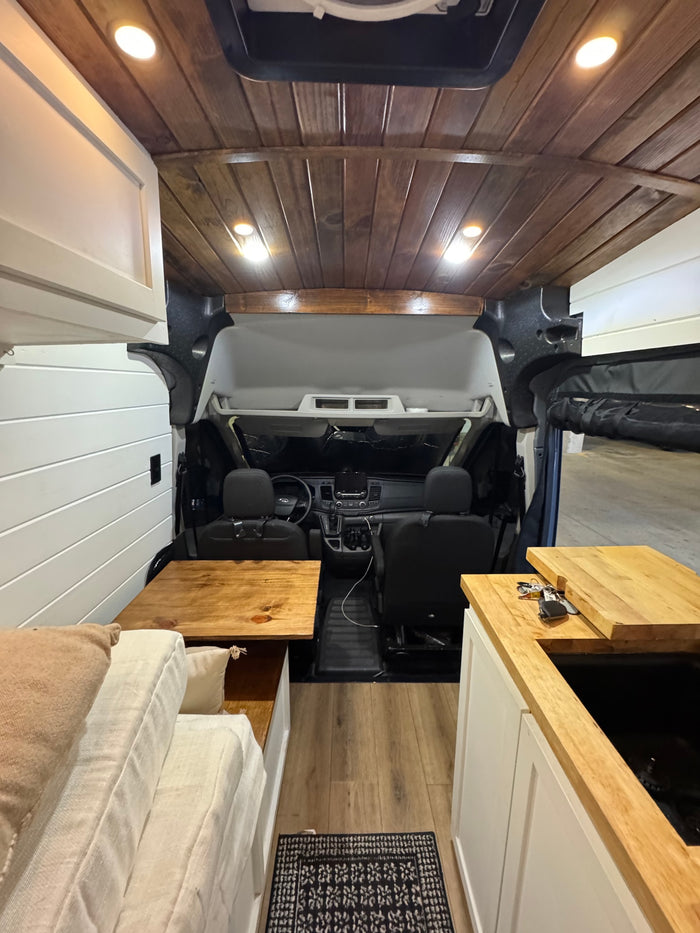 RV rental: Full interior view of a custom camper van, highlighting wood ceiling, kitchen, bed, and front cabin.